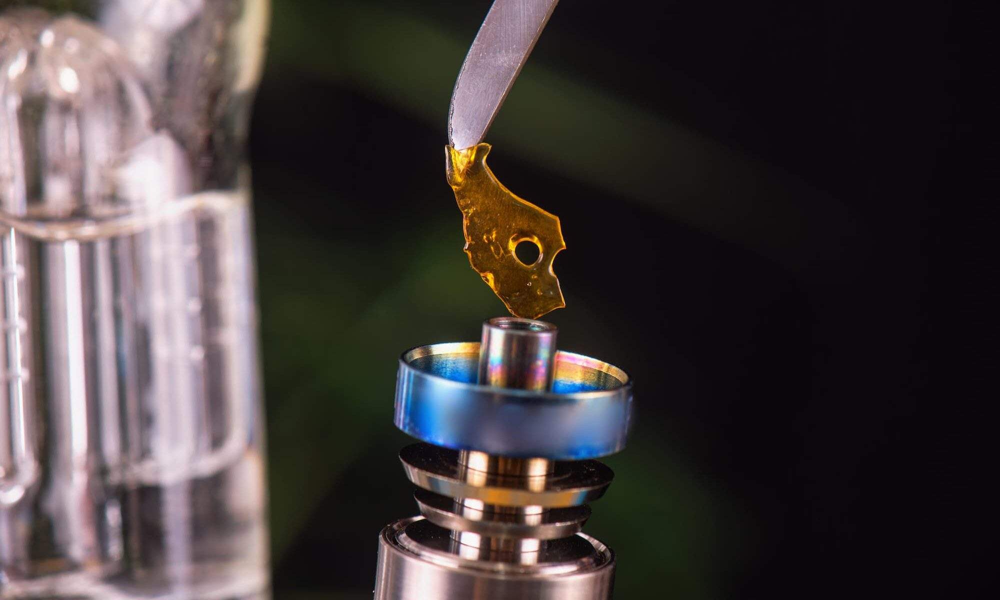 close up image of a cannabis concentrate being held by tweezers