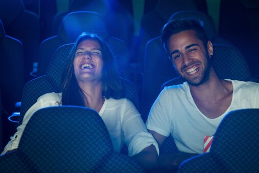 A woman and man at a movie theatre laughing