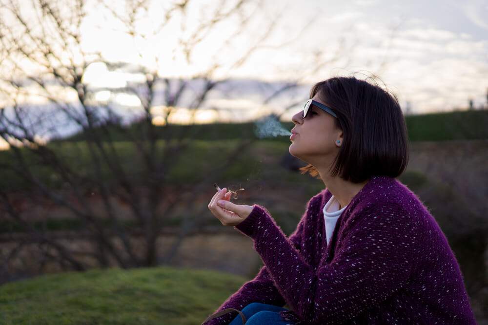 A woman smoking a joint outside